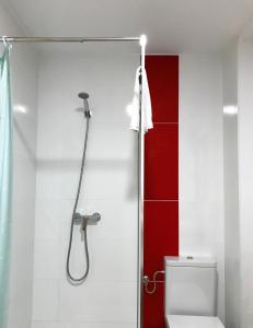 y baño con ducha, aseo y pared roja. en Casa Rural La Cambreta - Chulilla en Chulilla