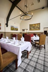 uma sala de jantar com mesas e cadeiras e um lustre em Stirling Highland Hotel- Part of the Cairn Collection em Stirling