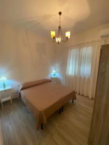 1 dormitorio con cama y lámpara de araña en La casetta degli ulivi, en Petrosino