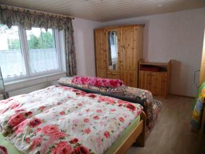 - une chambre avec 2 lits avec des fleurs rouges dans l'établissement FeWo Spreequelle, à Herrnhut