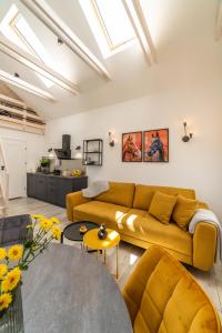 a living room with a yellow couch and a table at Apartamenty Pod Dębami in Sarbsk