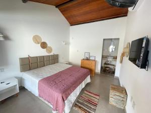 a bedroom with a bed and a flat screen tv at A CASA DA PRAIA DO FORTE in Praia do Forte