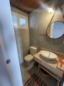 W łazience znajduje się umywalka, toaleta i lustro. w obiekcie A CASA DA PRAIA DO FORTE w mieście Praia do Forte