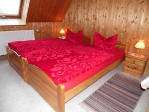 um quarto com uma cama grande com lençóis e almofadas vermelhas em Doppelzimmer Oybin em Herrnhut