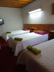 ein Hotelzimmer mit 3 Betten und grünen Handtüchern darauf in der Unterkunft Hotel Real del Campo in Quetzaltenango