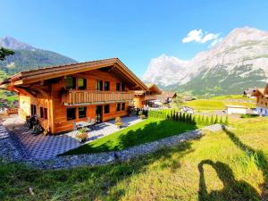 uma casa de madeira nas montanhas com um relvado verde em Chalet Eigernordwand em Grindelwald