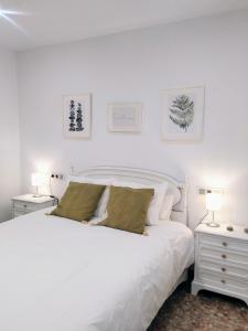 a white bedroom with a large white bed and two lamps at Balcón del Cardenal in Baeza