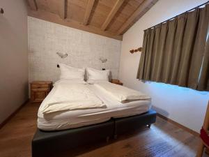 uma cama com lençóis brancos e almofadas num quarto em Hotel Le Alpi em Livigno