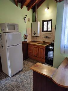 uma cozinha com um frigorífico branco e um lavatório em Cabañas El Aguaribay em Capilla del Monte