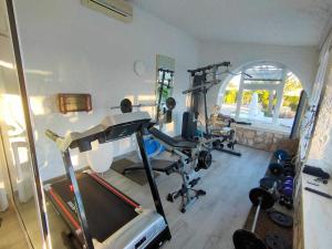 una habitación con gimnasio con cinta de correr y pesas en La Villa Romantica Résidence de vacances Les Tres Cales Espagne, en Les tres Cales