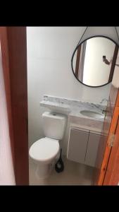 La salle de bains est pourvue de toilettes blanches et d'un miroir. dans l'établissement Apartamento aconchegante em frente à praia., à Ubatuba