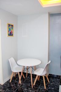 - une table blanche et 2 chaises blanches dans une pièce dans l'établissement A' BASICS APARTMENTS & SUITES, à Ibadan