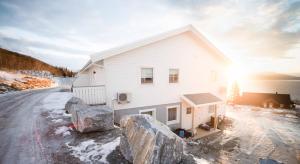 une maison blanche avec des rochers devant elle dans l'établissement Destination Senja - Vangsvik, à Brygghaugen