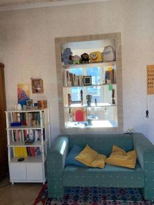 sala de estar con sofá azul y estante para libros en Cozy Apartment in T'bilisi en Tiflis