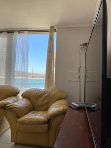 a living room with a couch and a large window at Lindo duplex frente al Mar in Coquimbo