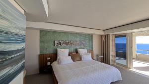 a bedroom with a large bed and a large window at The Marvel Beach House in Cape Town