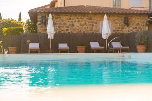 a swimming pool with chairs and white umbrellas at Si Montalcino Hotel in Montalcino
