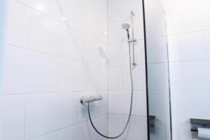 a shower in a white tiled bathroom at Harbour Hotel IJmuiden in IJmuiden