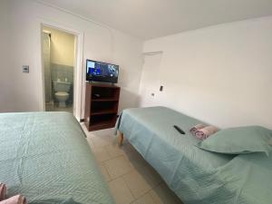 pokój hotelowy z 2 łóżkami i telewizorem w obiekcie Hostal Dolegant Pichilemu 2 w mieście Pichilemu