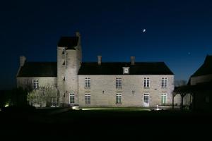 un viejo castillo de noche con la luna en el cielo en Grand gîte de la Ferme De La Tourelle, en Longues-sur-Mer