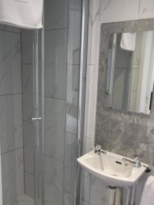 a bathroom with a shower and a sink and a mirror at Holmeleigh Hotel in Blackpool