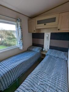 two beds in a small room with a window at PEACEFUL HOMELY Caravan IN LOVELY CUL DE SAC Littlesea Haven Weymouth in Weymouth
