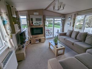 ein Wohnzimmer mit einem Sofa und einem TV in der Unterkunft PEACEFUL HOMELY Caravan IN LOVELY CUL DE SAC Littlesea Haven Weymouth in Weymouth