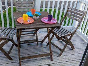 een houten tafel met twee borden en twee stoelen op een veranda bij PEACEFUL HOMELY Caravan IN LOVELY CUL DE SAC Littlesea Haven Weymouth in Weymouth