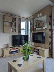 a living room with a tv and a coffee table at PEACEFUL HOMELY Caravan IN LOVELY CUL DE SAC Littlesea Haven Weymouth in Weymouth