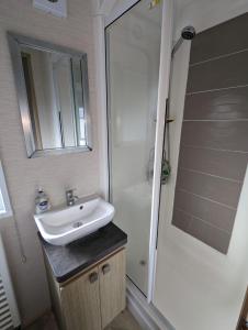 uma casa de banho com um lavatório e um chuveiro em PEACEFUL HOMELY Caravan IN LOVELY CUL DE SAC Littlesea Haven Weymouth em Weymouth