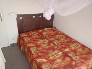 1 cama con edredón rojo en una habitación en Villa avec piscine entre plage et Siné Saloum, en Palmarin