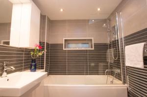 a bathroom with a tub and a sink and a shower at Harbour Master in Kilmelfort