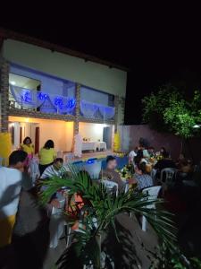 a group of people sitting at tables in a restaurant at night at Pousada Aconchego Santarém in Barreirinhas