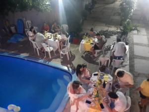a group of people sitting at tables next to a pool at Pousada Aconchego Santarém in Barreirinhas