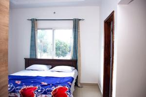 1 Schlafzimmer mit einem Bett mit einem Fenster und einer Tagesdecke in der Unterkunft Jobz Luxury Rental - White Villa in Brufut