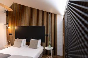 a bedroom with a white bed and a wooden wall at Dark Studio in São Roque