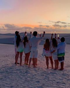 a group of people standing on the beach at sunset at Pousada Aconchego Santarém in Barreirinhas
