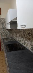 una cocina con armarios blancos y una pared de azulejos en Casa da Carmine a Tursi, en Tursi