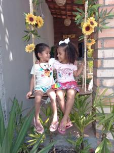 two little girls sitting on a swing at Pousada Aconchego Santarém in Barreirinhas