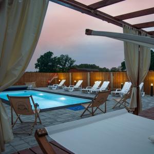 a patio with a pool and chairs and a table at Apartamenty Pod Dębami Stadnina Koni SPA Jezioro i Morze Sarbsk in Sarbsk