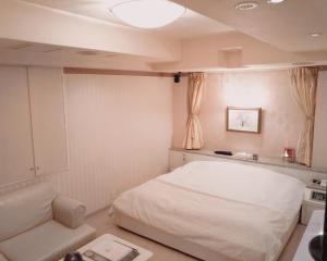 um quarto com uma cama branca e um sofá em ＳＴＡＲＲＥＳＯＲＴ　Ｉ em Sayama