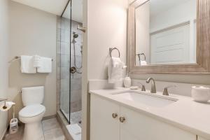 La salle de bains est pourvue de toilettes, d'un lavabo et d'un miroir. dans l'établissement Modern Condo with Game Room in Downtown New Orleans, à La Nouvelle-Orléans