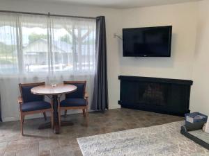 een woonkamer met een tafel en stoelen en een televisie bij Waterway Inn in Indian River