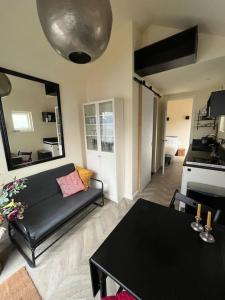 uma sala de estar com um sofá preto e uma mesa em Renovated & private Tinyhouse Den Haag short stay appartment em Haia