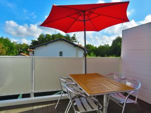 a table and chairs with a red umbrella on a balcony at Lodge Mendia in Anglet