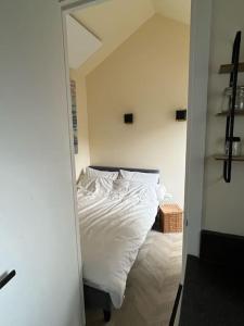 een slaapkamer met een bed met witte lakens en een spiegel bij Renovated & private Tinyhouse Den Haag short stay appartment in Den Haag