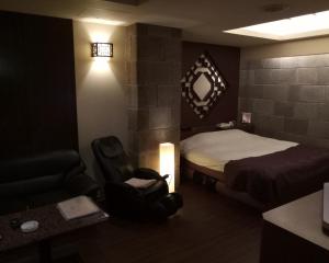 um quarto de hotel com uma cama e uma cadeira em ＳＴＡＲＲＥＳＯＲＴ　Ｉ em Sayama