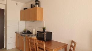 małą kuchnię z drewnianym stołem i kuchenką mikrofalową w obiekcie Workers-Sleep-Station w Kolonii