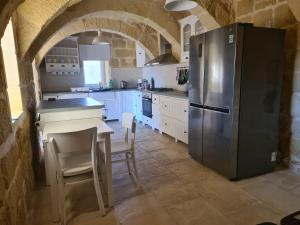 eine Küche mit einem Kühlschrank und einem Tisch mit Stühlen in der Unterkunft Farmhouse Villa in Gozo with large pool & garden in Birbuba
