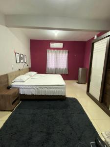 a bedroom with a bed and a purple wall at Ilha do amor in Camocim +12 photos